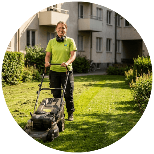Gräsklippning av grönytor vid ett flerbostadshus som del av löpande utemiljöskötsel. En ur personalen från Renew Service har stannat upp för att le mot kameran